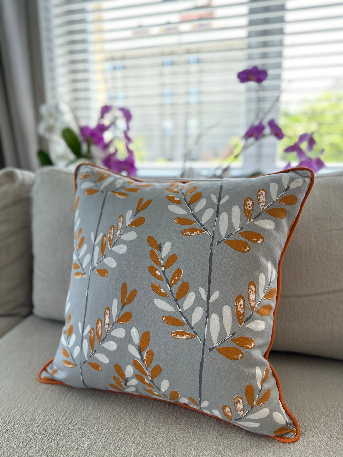 Bej kanepe üzerinde Leaf gri-turuncu 50×50 cm pamuk kırlent kılıfı